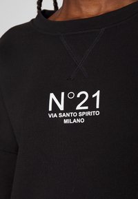 Black sweatshirt made of soft fabric; features a crew neckline and white printed text: "N°21 VIA SANTO SPIRITO MILANO" on the front.