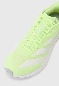 Scarpa da corsa verde neon con tomaia in rete, accenti bianchi, chiusura con lace e un design leggero. Presenta una superficie testurizzata e una forma aerodinamica.