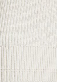 Tessuto a maglia bianco con una texture a coste verticali. Filato morbido e spesso crea un aspetto accogliente, con una finitura liscia ed uniforme.