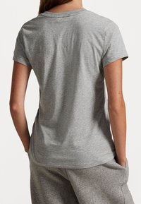 Szara bawełniana koszulka z krótkimi rękawami, okrągłym dekoltem i luźnym krojem. Gładka tekstura z minimalnymi detalami szwów z tyłu.