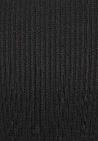 Texture de tissu en maille côtelée noire avec des lignes verticales et une surface légèrement rugueuse.