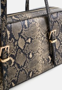 Handtasche mit Schlangenledermuster in Beige und Schwarz, ausgestattet mit goldfarbenen Beschlägen und zwei Tragegriffen oben. Reißverschluss verläuft entlang des oberen Randes.