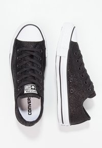 Sneakers neri in tela con superficie testurizzata, punta in gomma bianca e suola bianca a contrasto. Presentano occhielli neri e un sistema di lacci.