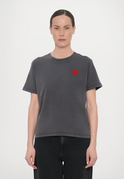 Grå bomulds T-shirt med korte ærmer, der har en lille rød hjerte- og pil-broderi på venstre bryst. Lidt løs pasform med en rund udskæring.