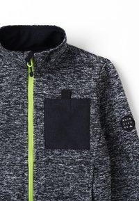 Dresowy polarowy zamek w kolorze węgla z teksturowanym wykończeniem. Posiada limonkowy zamek, kieszeń na piersi oraz naszywkę z logo marki.