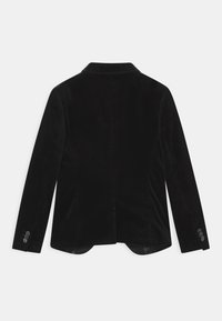 Černý sametový blazer s klopovým límcem, s jedním rozventilováním na zadní straně a knoflíkovými manžetami. Hladká textura a přiléhavý střih.