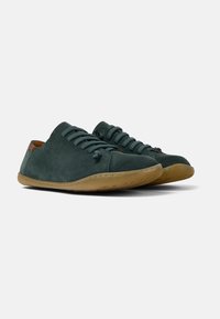 Scarpe in suede verde scuro con punte arrotondate, design con lacci e suola in gomma marrone chiaro; texture liscia e dettagli minimi.