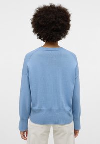 Maglione lavorato a maglia azzurro chiaro con una texture a coste, spalle basse e scollatura rotonda. Presenta un orlo dritto e polsini aderenti.