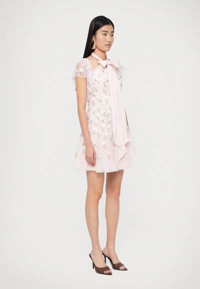 Svetloružové šaty s kvetinovou výšivkou, tylovou sukňou, krátkymi volánovými rukávmi a mašľou na zaväzovanie. Doplnok tvoria hnedé podpätkové mule s otvorenou špičkou.