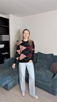 Πουλόβερ με μαύρο, ροζ και μπορντό σχέδιο αργυλέ; μαλακή υφή; στρογγυλή λαιμόκοψη. Συνδυάζεται με ανοιχτό μπλε τζιν και αθλητικά παπούτσια.