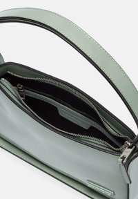 Borsa a tracolla in pelle verde chiaro con interni neri. Presenta una chiusura a zip, tracolla regolabile e dettagli testurizzati. All'interno, una tasca con zip.