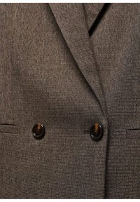 Hnědý texturovaný blazer se zdvojeným zapínáním, dvěma tmavými knoflíky a jemnými vzory v látce.