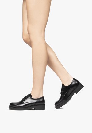Scarpe nere in pelle con lacci, punta arrotondata, texture liscia e tacco spesso, caratterizzate da quattro bottoni e una finitura lucida.
