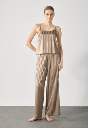Satin loungedräkt i dämpad beige med vertikala ränder. Den ärmlösa toppen har en lös passform och är i kombination med vida byxor.