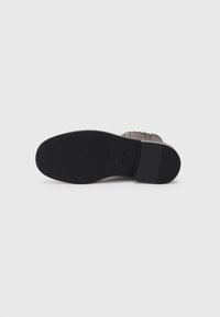 Shoe sole featuring a black rubber base with a textured, ridged surface for grip. The design is flat with a slight heel and minimal hardware.