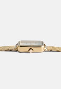 Χρυσό-τονικό τετράγωνο ρολόι με υφασμένη αλυσίδα, διαθέτοντας απλή πρόσοψη, μινιμαλιστικούς δείκτες ωρών και πλάγιο κουμπί για ρύθμιση.