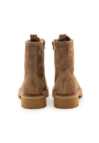 Botas de tobillo de ante marrón con un acabado texturizado, que cuentan con un zipper lateral, tiradores y una suela de goma en contraste.