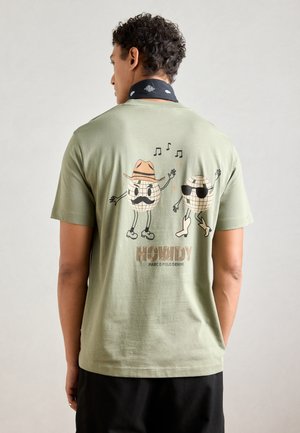 Oliven grøn bomulds t-shirt med legesyg grafik af to diskokuglefigurer iført hatte og solbriller, med teksten "HOWDY."