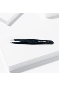 Pinces à épiler Tweezerman avec une finition pailletée noire brillante, dotées d'une tête inclinée pour une précision optimale. Matériau en métal robuste, design épuré.