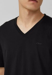 Zwarte V-hals T-shirt gemaakt van zachte katoenstof, met een subtiel s.Oliver-logo op de borst. Gladde textuur en slim fit ontwerp.