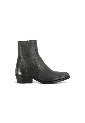 Bottine en cuir noir avec un petit talon bloc, bout arrondi et fermeture éclair sur le côté sur fond blanc.