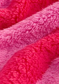 Fuzzy blanket featuring soft, plush texture in varying shades of pink, with wavy patterns creating depth and warmth.