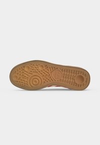 Sål på sko med tan-farvet gummimønster med cirkulære og geometriske mønstre samt Adidas-logo nær hælområdet.