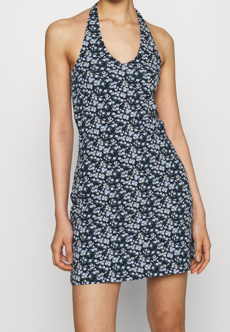 Blommig halterneckklänning i mörkblått med små vita och ljusblå blommor. Figurformad design med djup urringning och mjukt tyg.