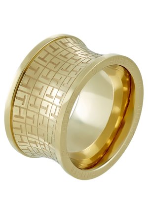 Brede gouden ring met gegraveerd geometrisch patroon en reliëf merknaam "Hilfiger" rond de buitenrand.