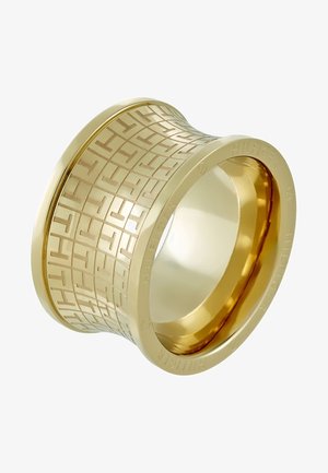 Brede gouden ring met gegraveerd geometrisch patroon en reliëf merknaam "Hilfiger" rond de buitenrand.