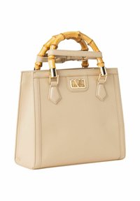 Beige leren handtas met een gestructureerde vorm, bamboehendel, gouden accenten en een logo plaatje aan de voorkant.