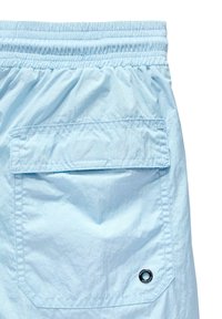 Lyseblå shorts med elastisk talje, som har en baglomme og et rundt mærke-logo som accent. Materialet ser let og glat ud.