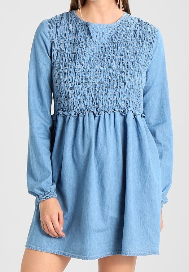 Denimmekko, jossa on rypytetty yläosa, pitkät hihat ja rypytetty helma. Vaalea sininen väri ja elastiset hihansuut tarjoavat rennon istuvuuden.