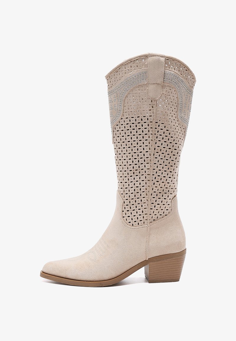 Bota western de gamuza beige con punta afilada, caña perforada y tacón apilado. Costuras decorativas notables y acentos texturizados.