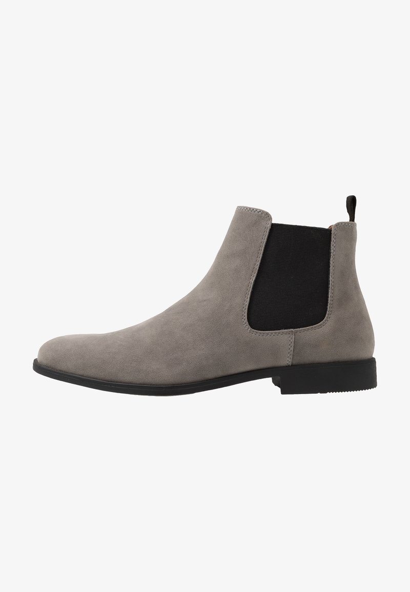 Bottine Chelsea en daim gris avec panneau latéral élastique noir, languette au talon et semelle basse noire, vue de côté extérieur.