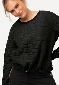 Sudadera negra acolchada con cuello redondo, tejido texturizado, puños acanalados y dobladillo con cordón. Presenta un patrón geométrico en toda su superficie.