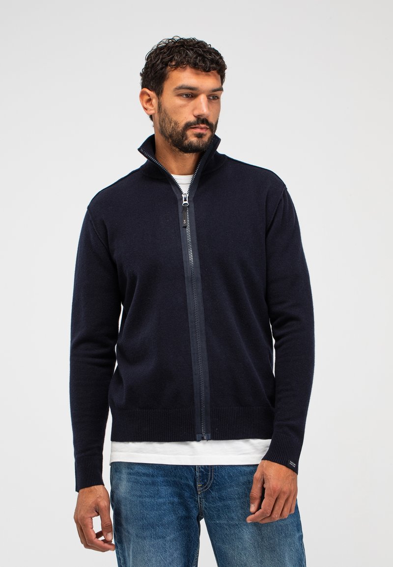 Marinefarbener Zip-Sweater mit hohem Kragen, gerippten Bündchen und Saum, aus weichem Material gefertigt und mit einem glatten Reißverschlussakzent an der Vorderseite versehen.