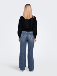 Wide-leg blue denim jeans with a faded finish, high waist, and two back pockets. Paired with a black textured sweater.