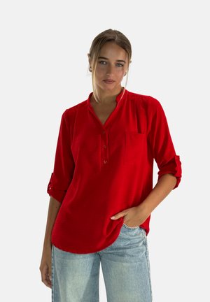 Camicia rossa con pattina abbottonata, tessuto strutturato e taschino sul petto. Presenta maniche arrotolate e una vestibilità rilassata.