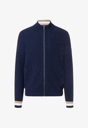 Suéter de punto azul marino con cremallera, cuello y puños acanalados, rayas beige y blancas en los puños y bolsillos laterales.