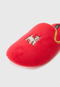 Rode fleece slipper met gouden rand en een witte geborduurde hond op de bovenkant. Zachte textuur en ronde vorm.