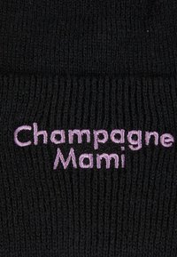 Svart strikket lue som har brodert teksten "Champagne Mami" i lys lilla, med ribbestruktur hele veien.