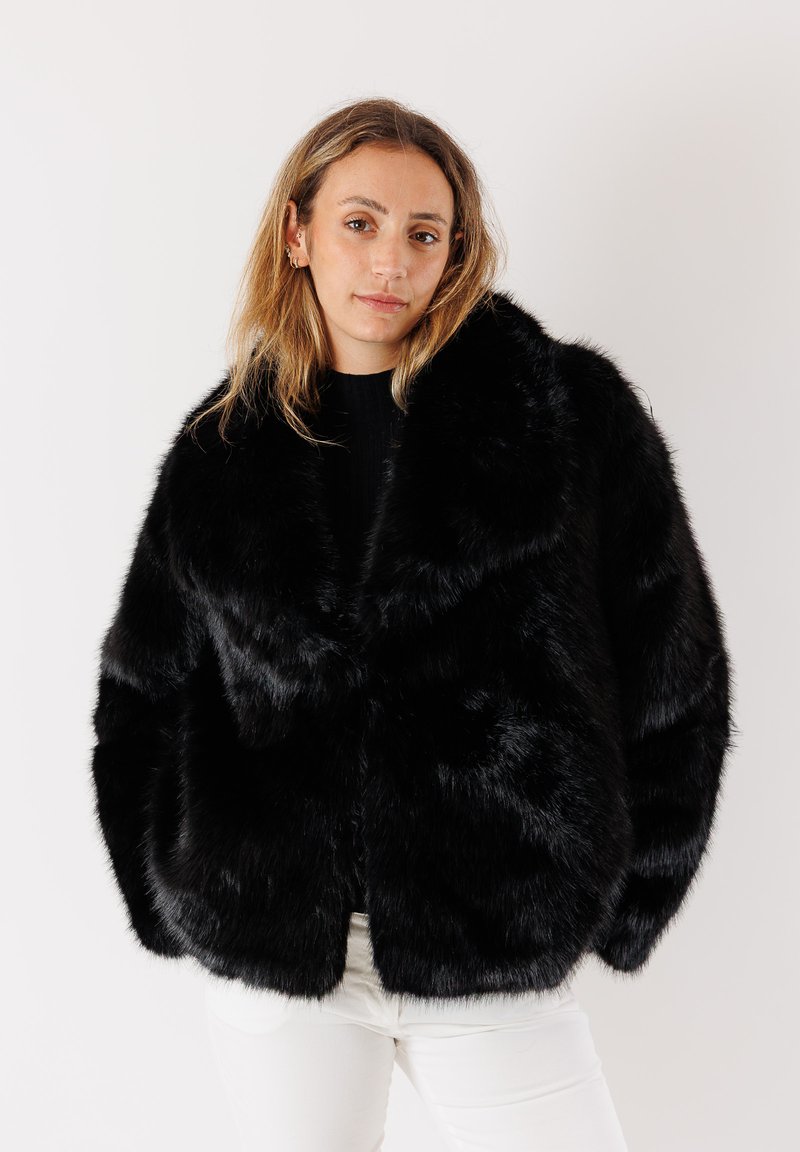 Cappotto in pelliccia sintetica nera con colletto ampio, vestibilità morbida e texture soffice, dotato di chiusura con bottoni e senza motivi visibili.
