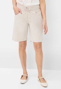 Shorts beiges jusqu'aux genoux avec une taille plate, des passants de ceinture et des poches. Fabriqués en tissu léger avec une texture lisse.