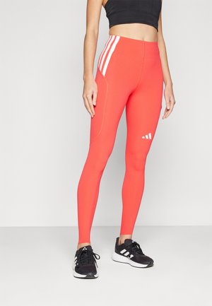 Red athletic leggings with white side stripes and logo. Made of smooth, stretchy material with a fitted design and seam detailing.