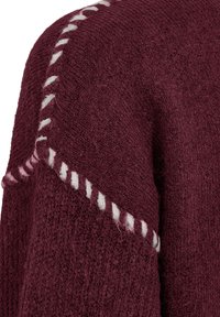 Bordeaux brei sweater met een gestructureerde afwerking, voorzien van witte en roze stiksels langs de schoudernaad.