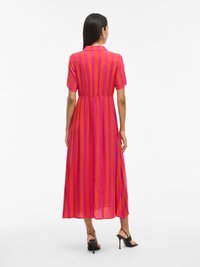 Roosa ja oranž triibuline midi kleit lühikeste varrukatega, vöökoht on rõhutatud ja siluett on voolav. Sobitatud mustade rihmadega kontsakingadega.