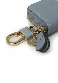 Portachiavi in pelle azzurro chiaro con zip e finiture dorate, dotato di un piccolo tag e attacco per il portachiavi. Texture liscia, design compatto.