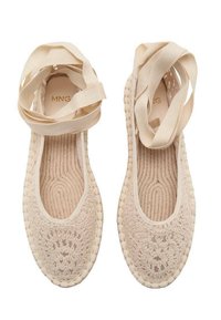 Espadrilles de crochet color beige con un upper texturizado, lados abiertos y una suela plana de yute, complementadas con largas cintas de tela.