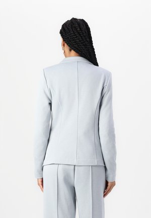 Blazer azzurro chiaro su misura con una texture liscia, presenta un colletto a revers e cuciture strutturate, abbinato a pantaloni su misura coordinati.